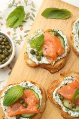  Tasty canapes with salmon, capers, cucumber and sauce on table, top view © New Africa