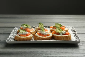  Tasty canapes with salmon, cucumber, cream cheese and dill on wooden table © New Africa