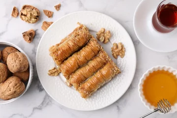  Eastern sweets. Pieces of tasty baklava, walnuts and tea on white marble table, flat lay © New Africa