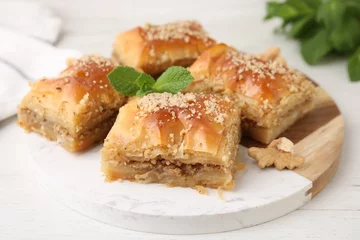 Poster Eastern sweets. Pieces of tasty baklava on white wooden table, closeup © New Africa