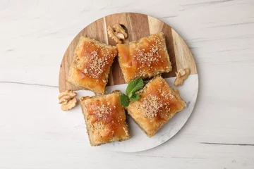 Tuinposter Eastern sweets. Pieces of tasty baklava on white wooden table, top view © New Africa