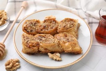  Eastern sweets. Pieces of tasty baklava, walnuts and tea on white tiled table, closeup © New Africa
