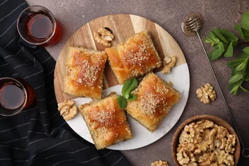  Eastern sweets. Pieces of tasty baklava, walnuts and tea on brown table, flat lay © New Africa
