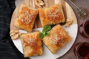 Fotobehang Eastern sweets. Pieces of tasty baklava and tea on brown table, flat lay © New Africa