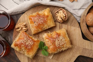 Tuinposter Eastern sweets. Pieces of tasty baklava and tea on wooden table, flat lay © New Africa