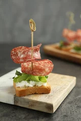 Gordijnen Tasty canape with salami, greens and cream cheese on grey table © New Africa
