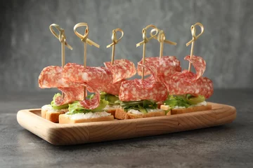  Tasty canapes with salami, greens and cream cheese on grey table © New Africa