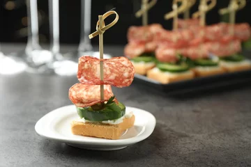 Schilderijen op glas Tasty canapes with salami, cucumber and cream cheese on grey table. Space for text © New Africa