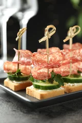  Tasty canapes with salami, cucumber and cream cheese on grey table, closeup © New Africa