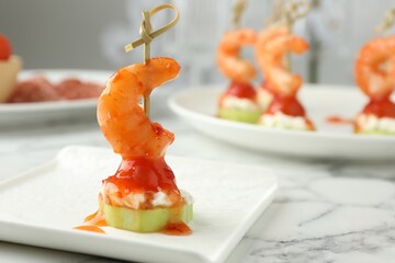 Tasty canape with shrimp, vegetables and cream cheese on white marble table, closeup. Space for text