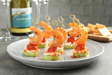 Tasty canapes with shrimps, vegetables and cream cheese on grey table