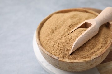 Dietary fiber. Psyllium husk powder in bowl and scoop on grey table, closeup. Space for text