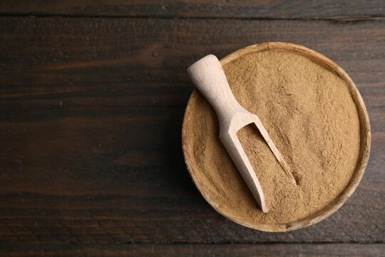 Dietary fiber. Psyllium husk powder in bowl and scoop on wooden table, top view. Space for text