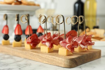 Different tasty canapes on white marble table, closeup