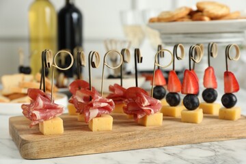 Different tasty canapes on white marble table, closeup