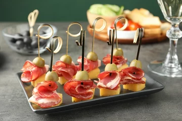 Plexiglas foto achterwand Tasty canapes with olives, prosciutto and cheese on grey table, closeup © New Africa
