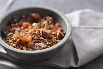 Gordijnen Tasty granola in bowl and napkin on gray table, closeup © New Africa
