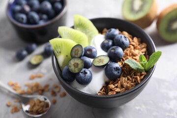 Tasty granola in bowl served on gray table, closeup