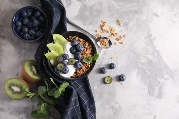 Outdoor kussens Tasty granola with yogurt, blueberries and kiwi in bowl on gray textured table, flat lay. Space for text © New Africa