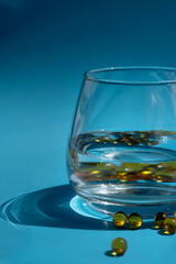 glass and yellow capsules on a blue background