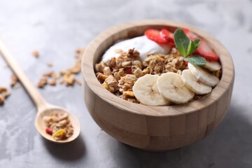 Tasty granola in bowl served on gray table, closeup