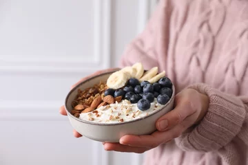 Outdoor kussens Woman holding bowl of tasty granola indoors, closeup. Space for text © New Africa