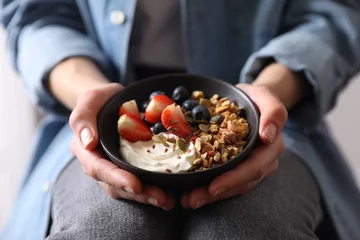 Fotobehang Woman holding bowl of tasty granola with berries, yogurt and seeds, closeup © New Africa