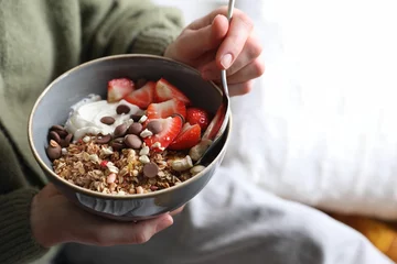 Badkamer foto achterwand Woman eating tasty granola with chocolate chips, strawberries and yogurt indoors, closeup. Space for text © New Africa