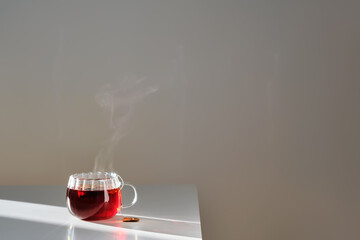 Glass mug with hot black tea on the table.