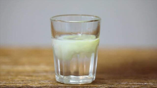 Dripping alcoholic propolis tincture into the water. Immiscible mixing in video