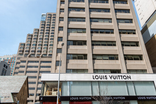 exterior building facade and sign of Louis Vuitton, a high end leather good store, located at 150 Bloor Street West in downtown Toronto, Canada