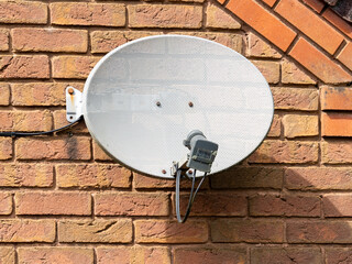 old weathered Digital satelite television receiver  dish multi channel decoder fixed to a brick wall