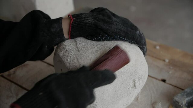 Close-up of man's hands creating a stone sculpture using  sandpaper.
