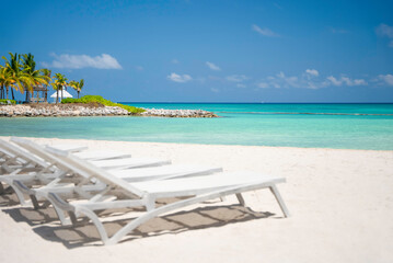 The row of empty sun loungers on a beautiful tropical beach with white sand and turquoise sea water...