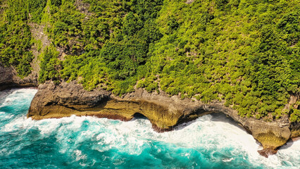 Amazing turquoise seascape. The rocks are washed by white foamy waves. Nusa Penida, Indonesia