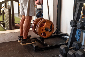 Dedicated anonymous man at the gym setting does calf raises on a weight-loaded machine with plates, focusing on lower body strength.