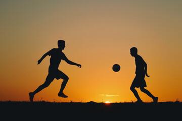 Two soccer players in silhouette playing at sunset