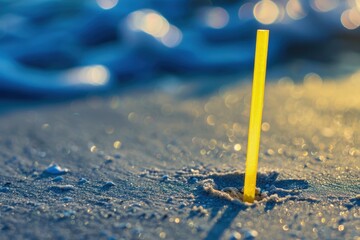 Yellow straw on the beach sand, concept of plastic waste, recycling, pollution prevention, environmental conservation. - obrazy, fototapety, plakaty