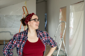 Beautiful smiling female designer in glasses is satisfied with the work done on the wall of the room. High quality photo