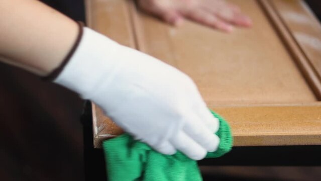 Person remonier worker in a gloves degreases the surface before painting a wooden product, kitchen facade close up