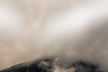 Mountain top covered in misty clouds. Areas of the cloud are transparent.
