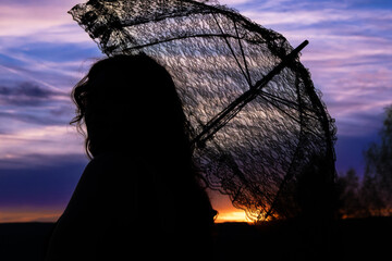 woman with a lace umbrella in the sunset