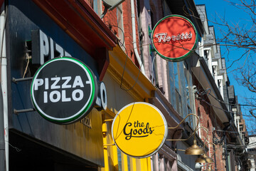 Obraz premium round signs of the Goods, Pizzaiolo, and Florette located along Queen Street West in Toronto, Canada