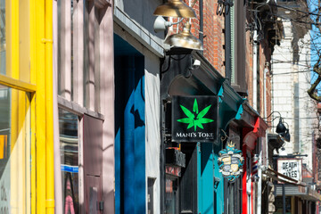 Fototapeta premium projecting signs on the side of buildings along (north) side of Queen Street West (Mani's Toke, a cannabis store, located at 1164 Queen Street West) in Toronto, Canada