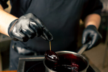 close up in a professional kitchen chef in black gloves soaks a delicacy in a burgundy sauce from a...