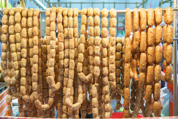 Pork and rice sausage or fermented hot dog northeastern isan thai style hanging in hawker stall for sale