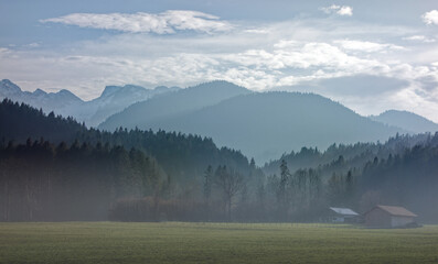 Fog over the meadow, farm house and the Bavarian mountains in the background, Alps, Bavaria,...