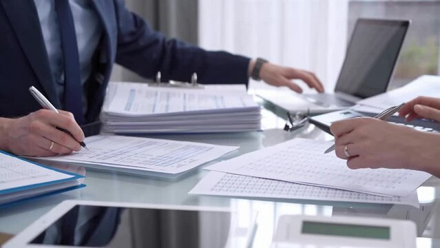 Business colleagues accountants or auditors reviewing financial data in office. Two professionals analyzing paper reports and using calculators. Audit and taxes