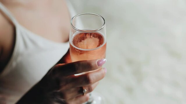 The girl is holding a glass of wine with a very pleasant pink color. Cool close-up