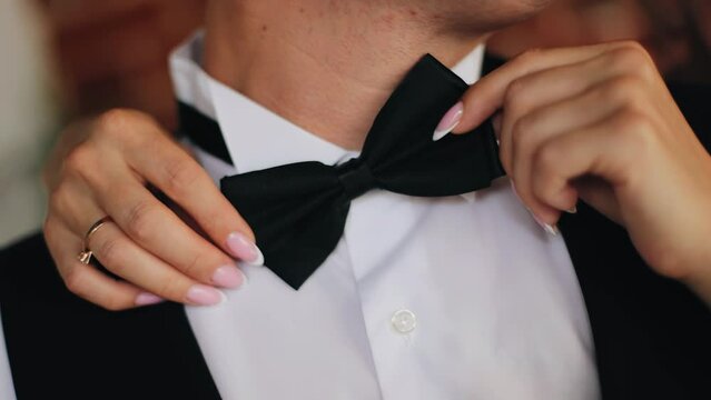 The girl adjusts her man's tie. She carefully moves the tie on him. Taken in close-up